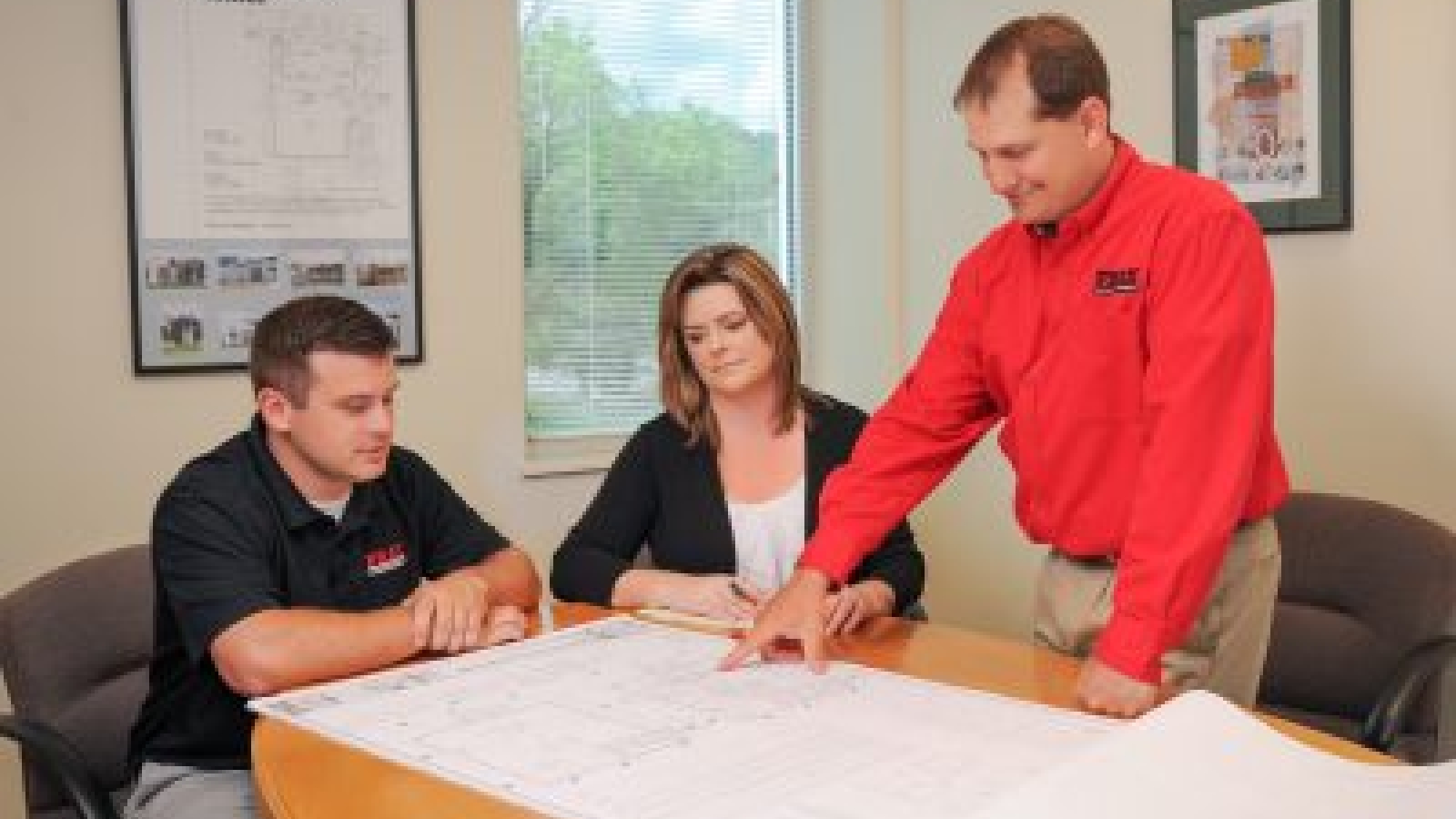 Angie, Brandon and Erich reviewing building plans on a table.
